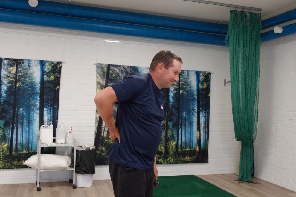 Henkilö kumartuneessa asennossa käsi alaselällä – kuvaa kehon reaktiota kuormitukseen ilman akuuttia kipua.