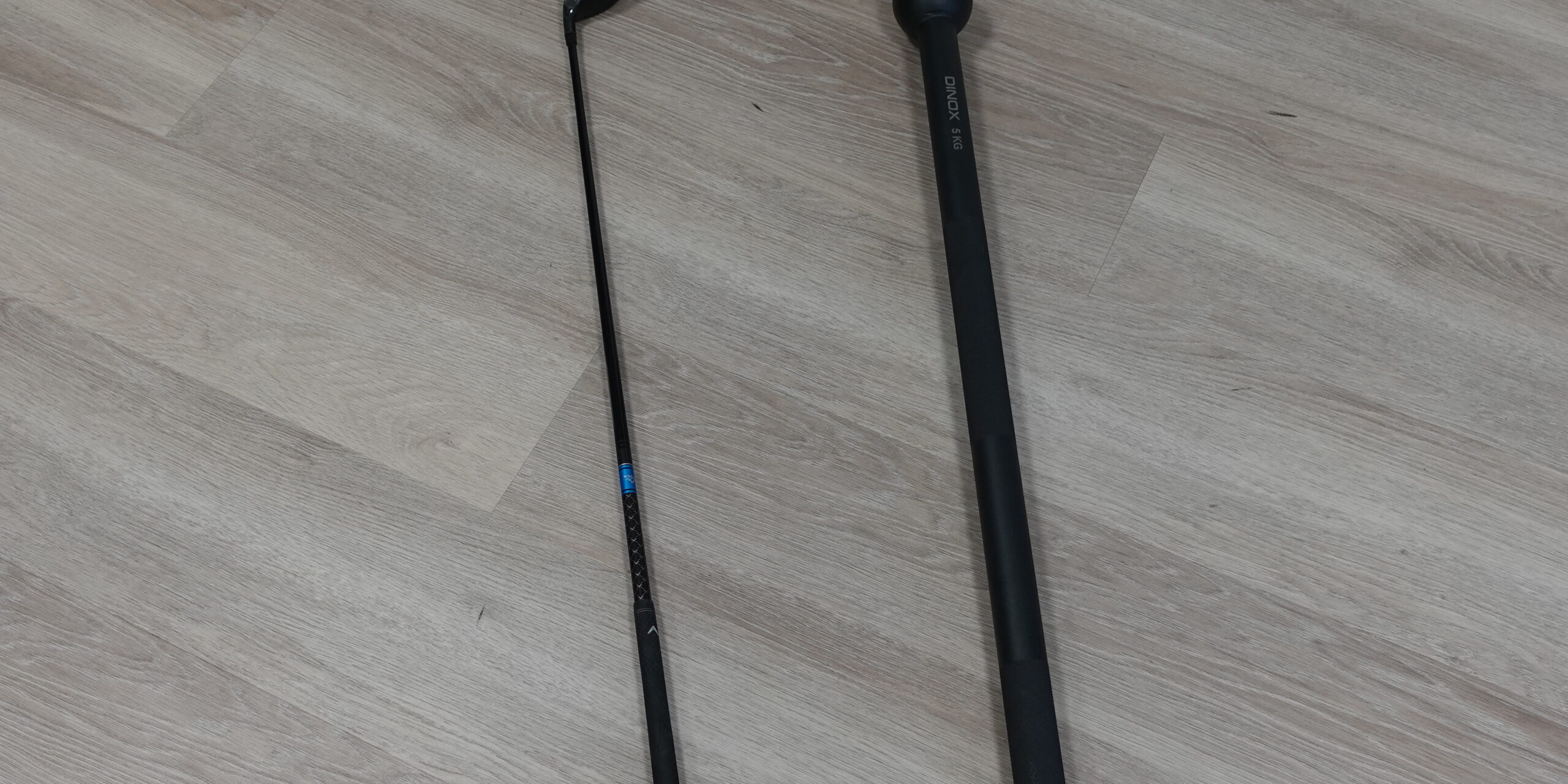 Golfmaila ja voimaleka vierekkäin lattialla symboloimassa harjoittelun kuormitusta ja palautumisen tarvetta golf-fysioterapiassa Joensuussa.