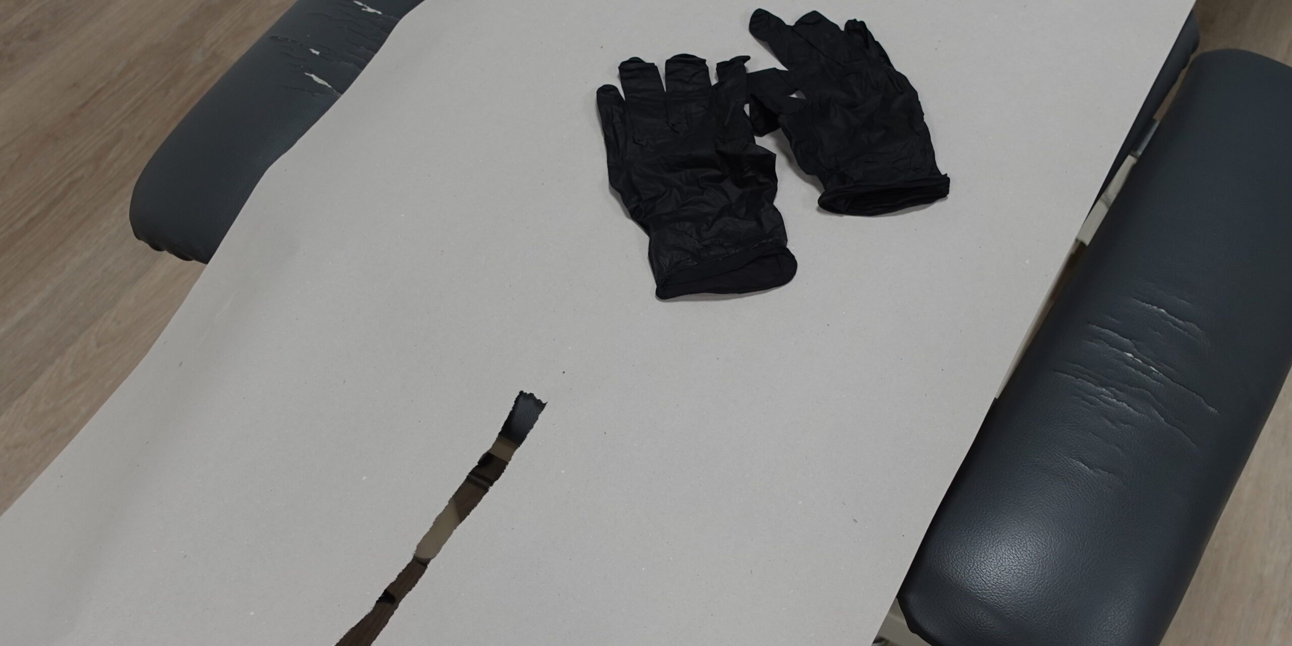 Valkoisella alustalla olevat kertakäyttöhanskat symboloivat purentalihashierontaa Joensuussa. Hanskat tarvitaan suun sisäpuolen lihasten käsittelyyn turvallisesti.