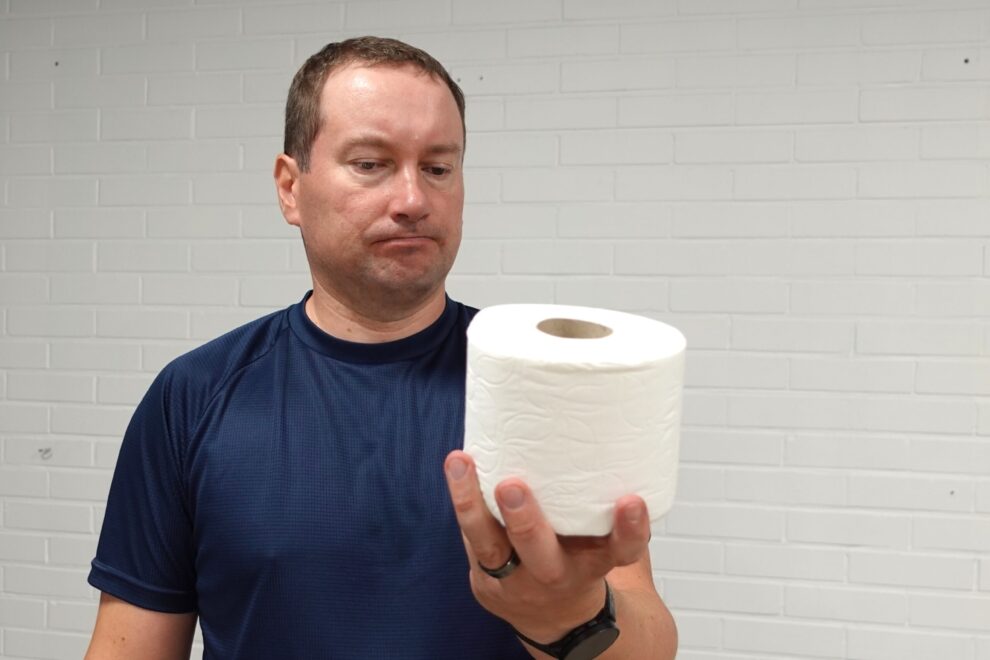 Henkilö havainnollistaa jäätyneen olkapään aiheuttamaa sisäkierron rajoitusta, joka vaikeuttaa arjen toimintoja kuten wc-käyntejä