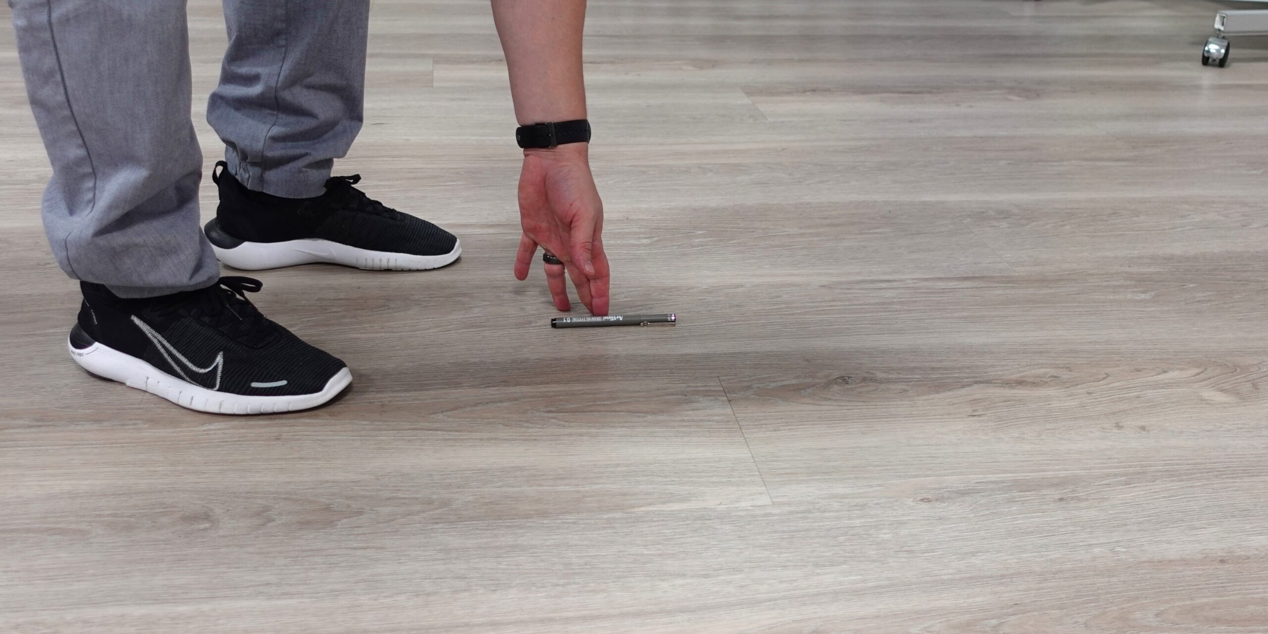 Kynän poimiminen lattialta selkäkiputilanteessa, liike joka usein provosoi yllättävää akuuttia selkäkipua