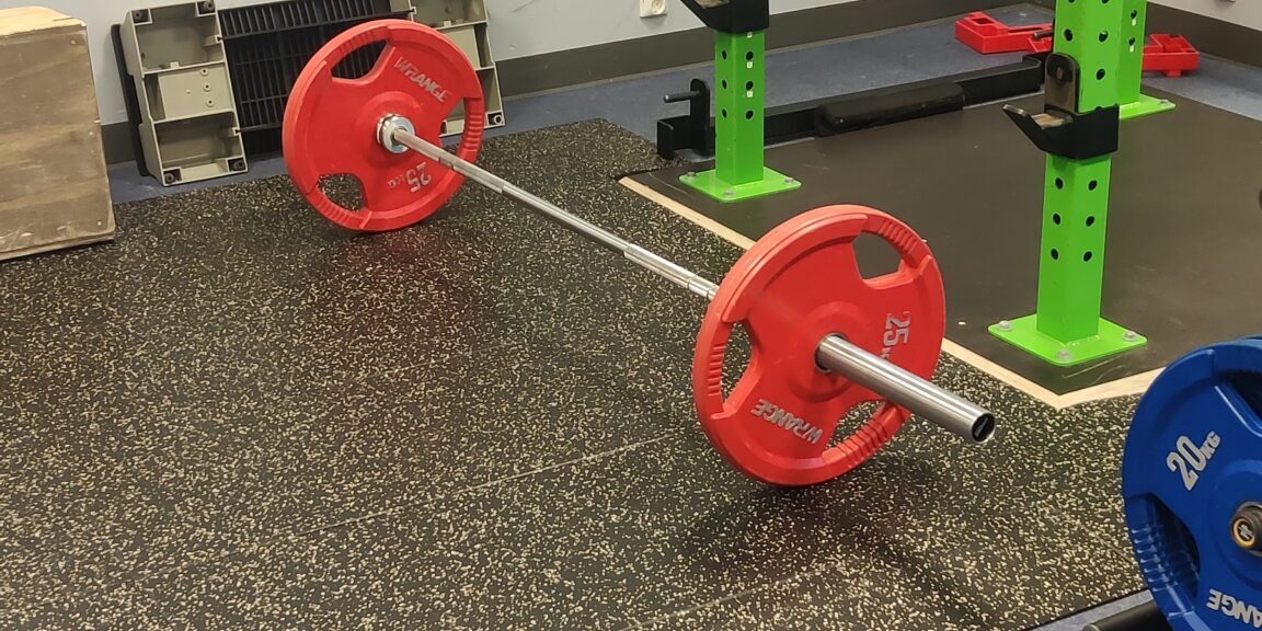 tanko ja levypainot kuntosalilla, kuvaamassa lähiliikuntapaikkojen merkitystä toimintakyvyn ja terveyden ylläpidossa