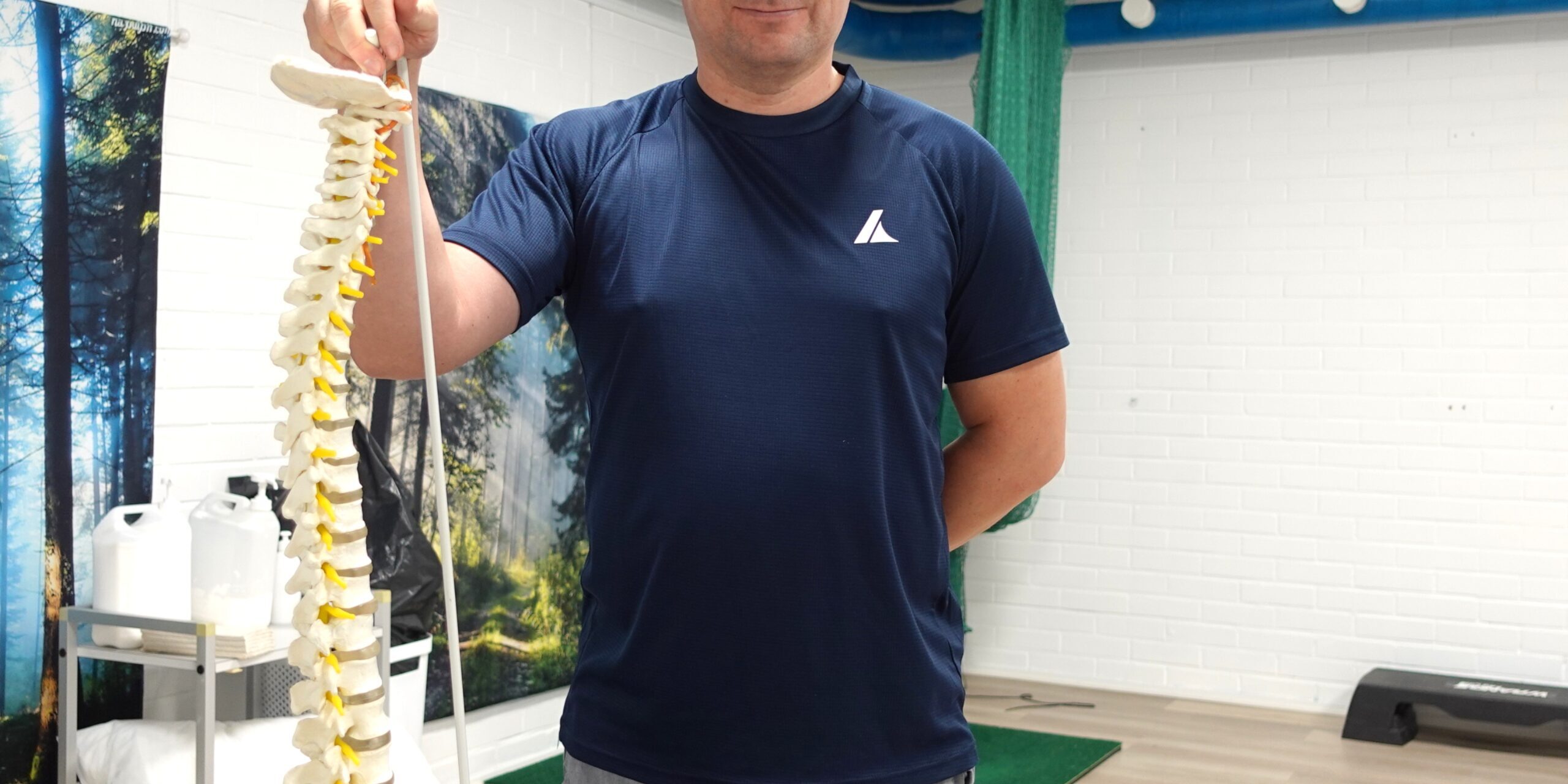 Fysioterapeutti Teppo Holopainen pitää selkärangan anatomista mallia kädessä fysioterapiavastaanotolla Joensuussa