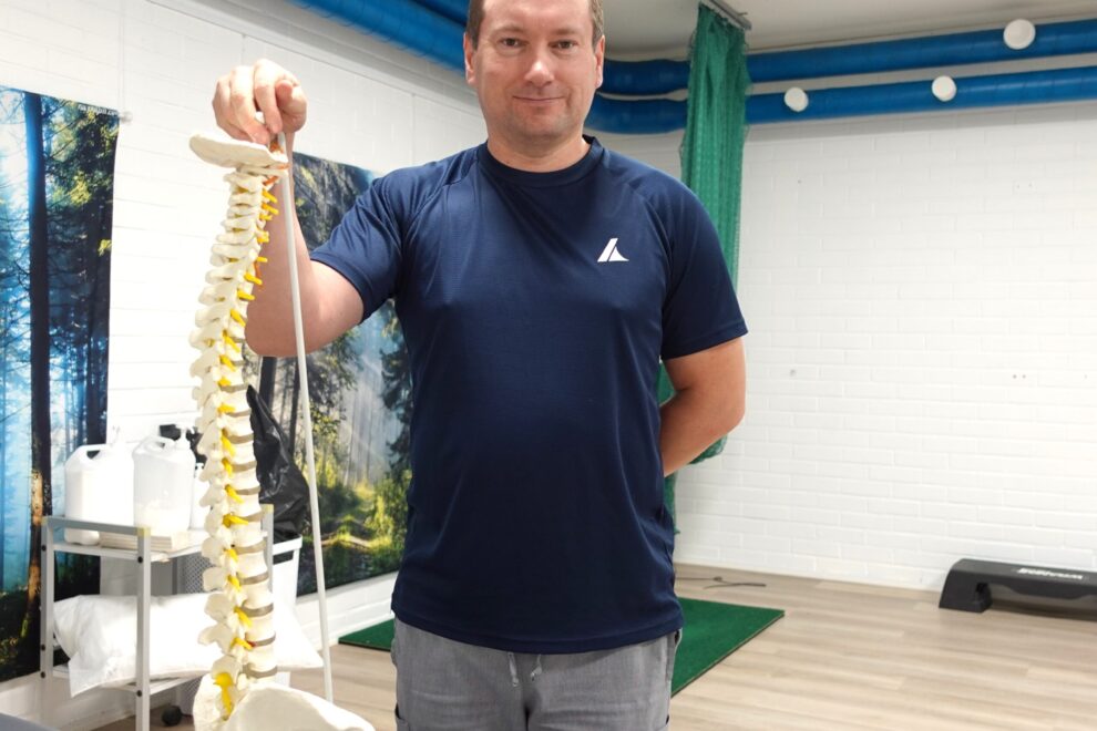 Fysioterapeutti Teppo Holopainen pitää selkärangan anatomista mallia kädessä fysioterapiavastaanotolla Joensuussa
